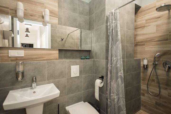 graue quadratische Fliesen in einem Badezimmer mit Holzdekor im Duschbereich