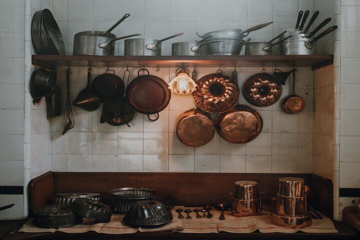 Glasierte helle Zellige Fliesen in einer traditionellen Küche mit einem Regal auf dem viele Töpfe und Backformen stehen